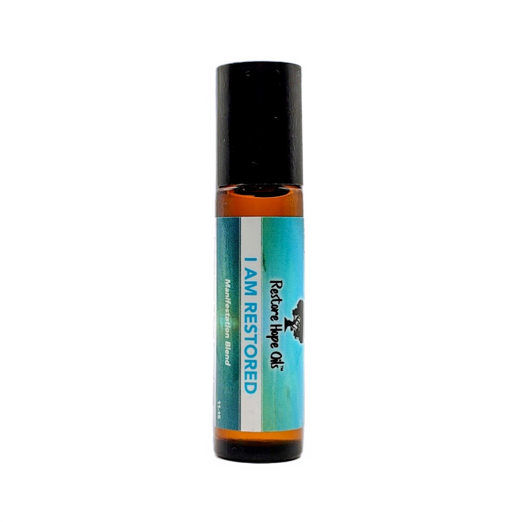 A roll-on bottle of 'I Am Restored' essential oil blend with a label that includes the product name and a brief description.
