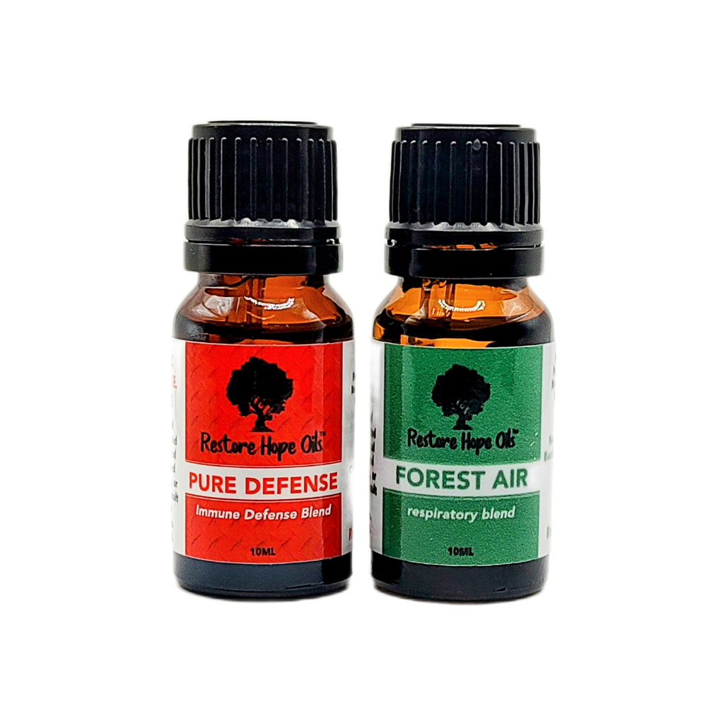 Two small bottles of essential oil blends labeled 'Pure Defense' and 'Forest Air', both with black lids and dropper tops.
